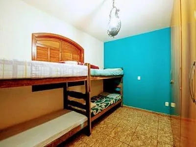 Quarto com dois beliches de madeira, parede azul-turquesa e guarda-roupa de portas de madeira